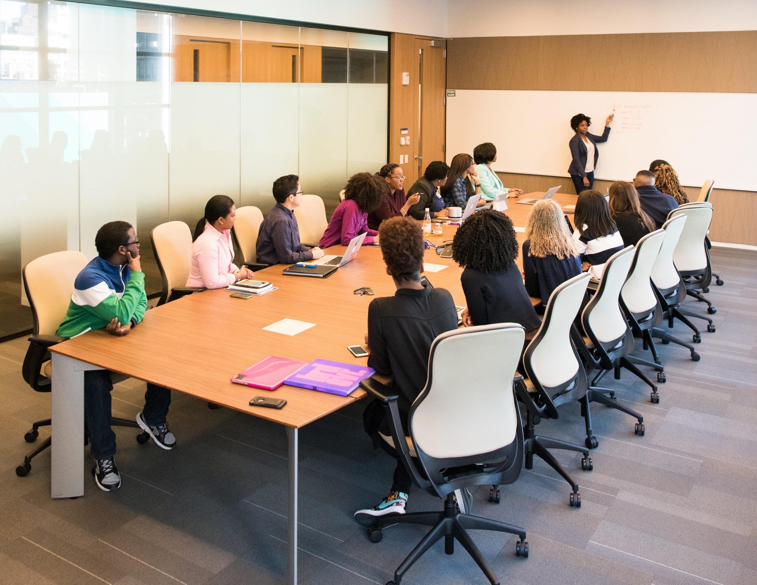 Lady presenting on a whiteboard to a group of young people